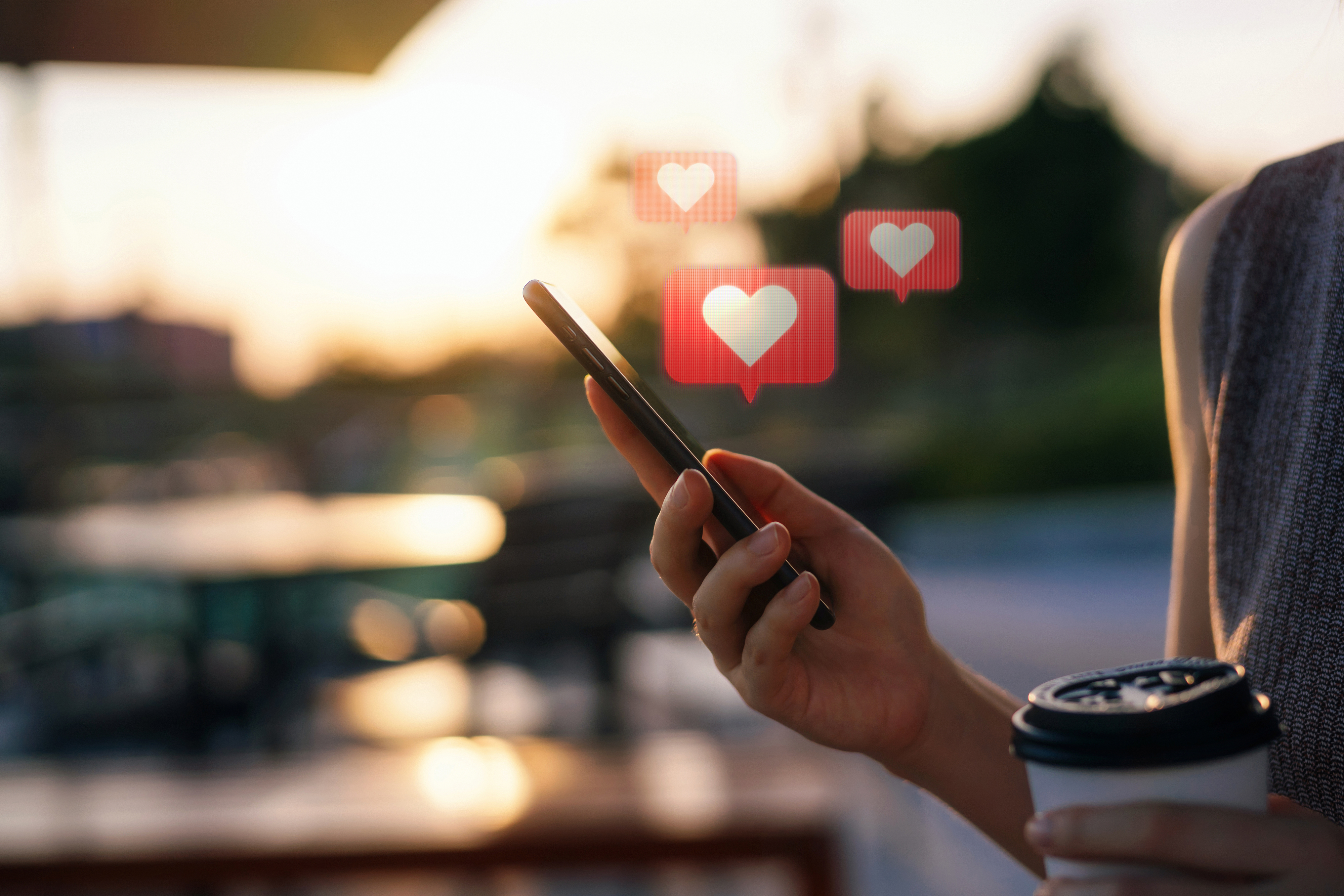 Person holding a phone with heart emojis above, indicating online dating or seeking connection