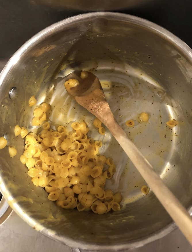 Pot with leftover macaroni and cheese and a wooden spoon inside