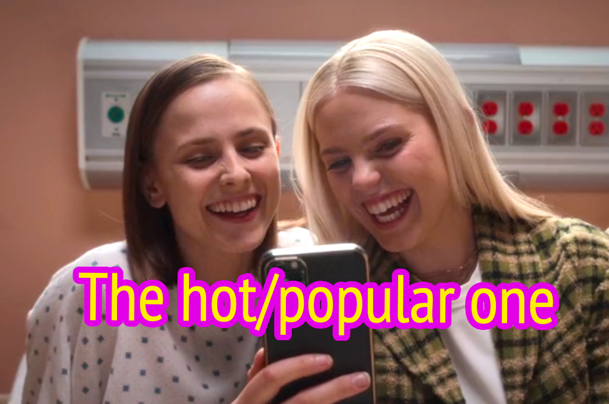 Two characters from "Sex Lives of College Girls" look at a phone and laugh together.