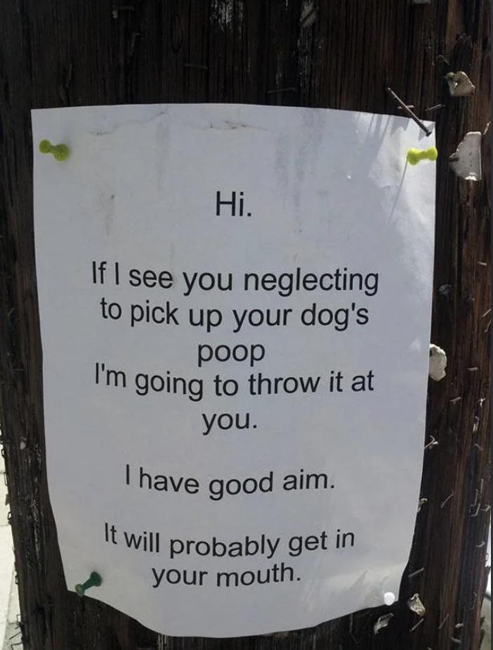 A warning sign on a post threatening to throw dog waste at owners who don&#x27;t clean up after their pets, claiming good aim