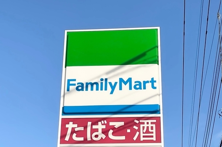 ファミリーマートの看板が、空と電線の背景の前にある。