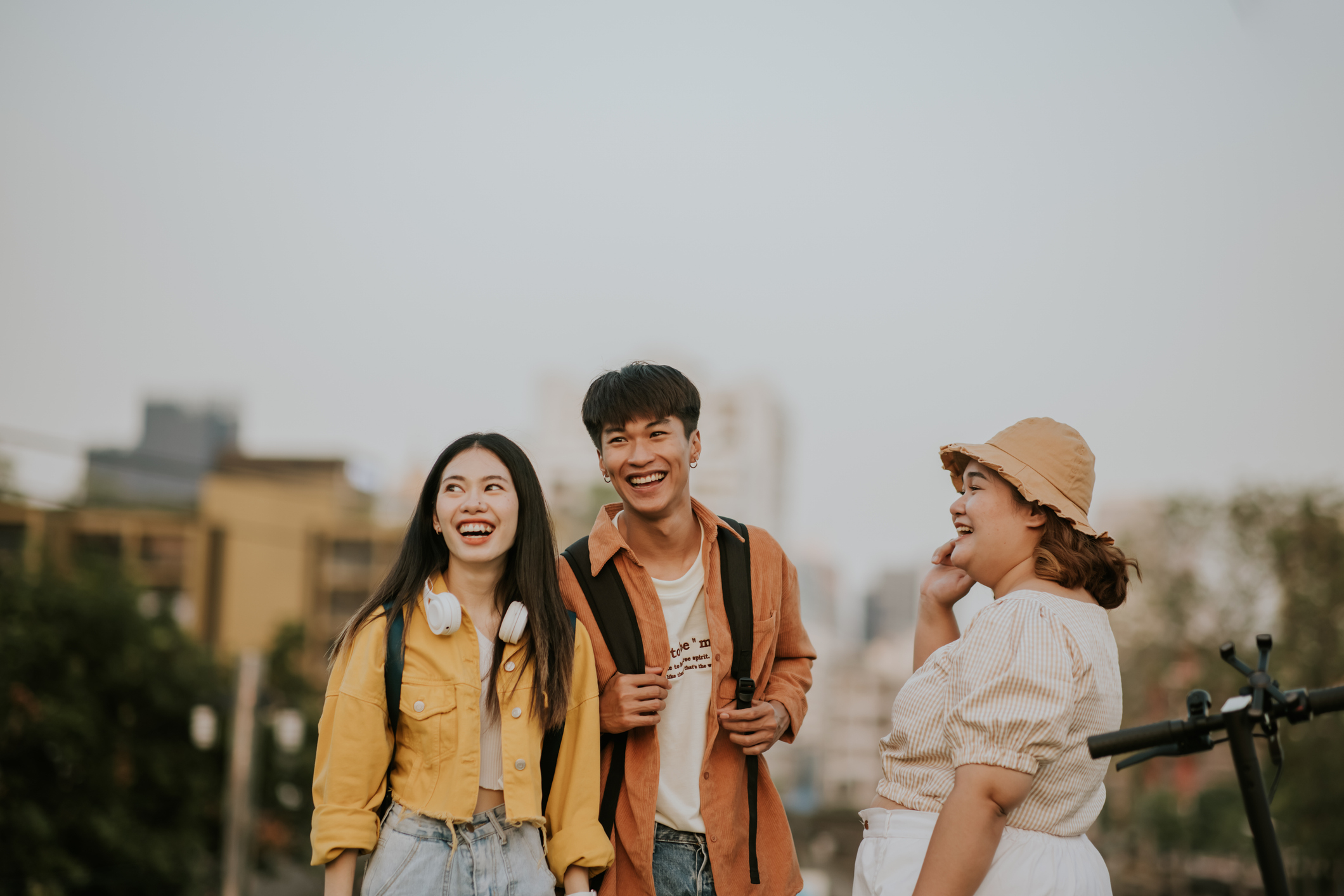Three friends smiling and walking outdoors, possibly coworkers enjoying a break