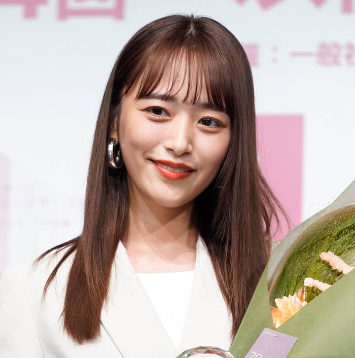 女性が微笑みながら花束を持っている。