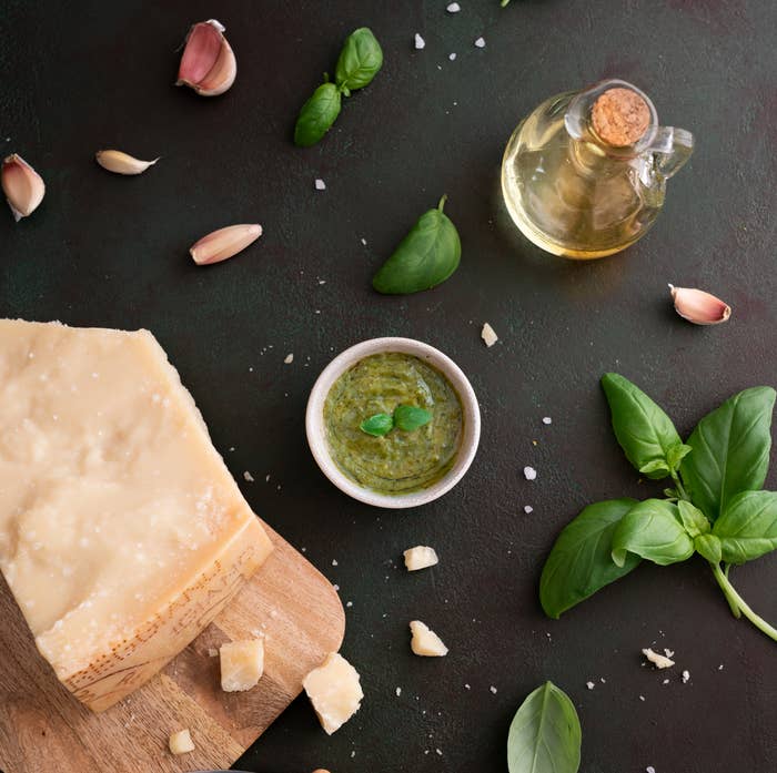 Ingredients for Italian cuisine with cheese, garlic, basil, and olive oil on dark surface