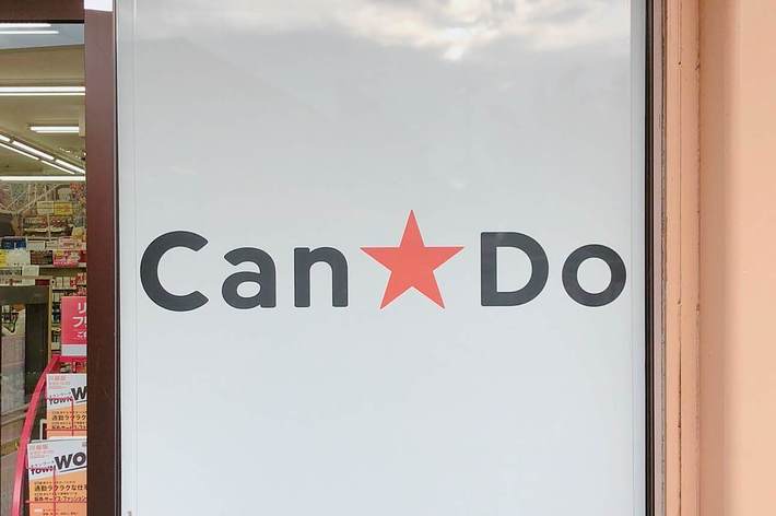 「Can Do」のロゴが入った店舗の入口ガラス扉。店内は広告で賑わっている。
