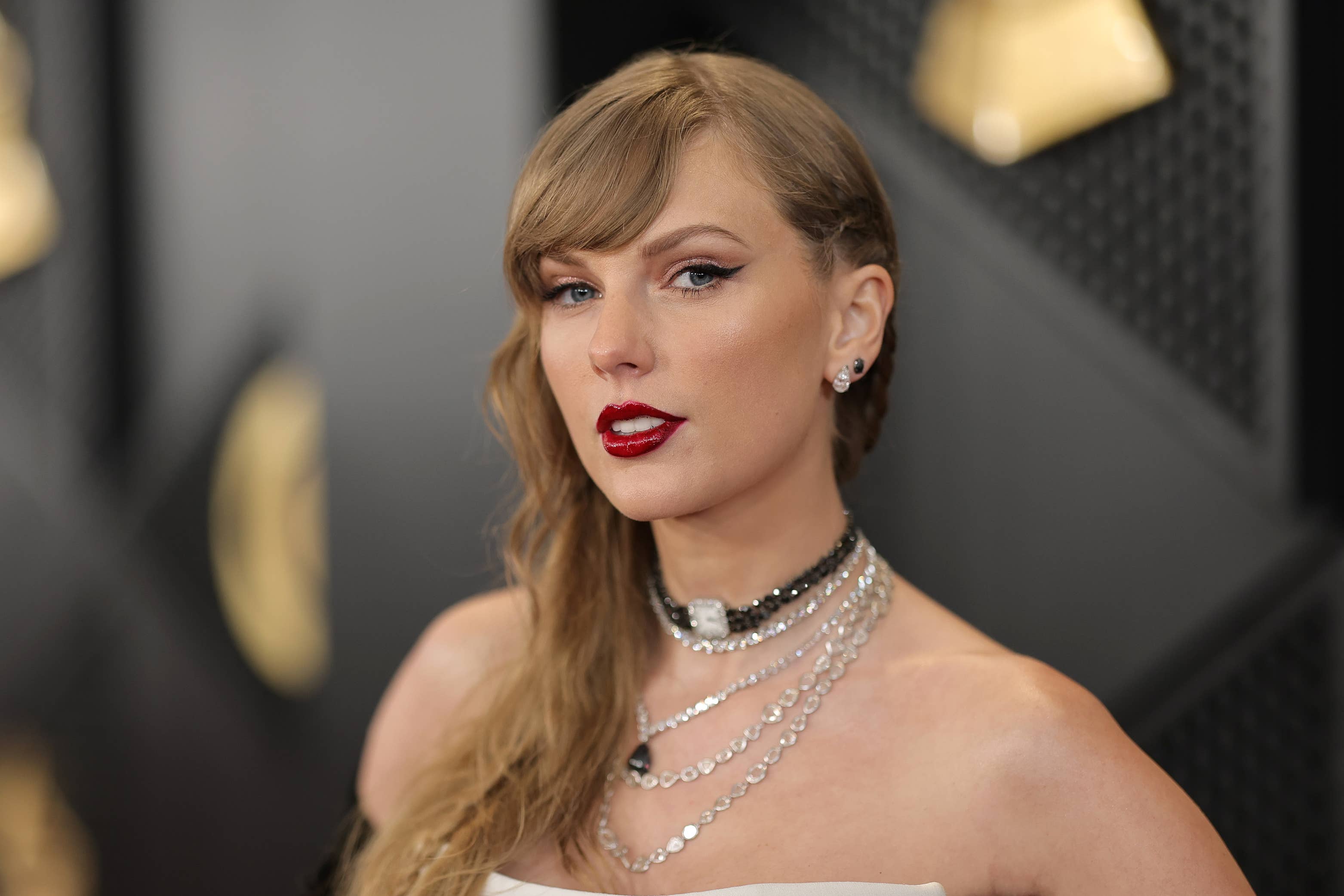 Taylor Swift wears an off-shoulder dress with layered necklaces at an event