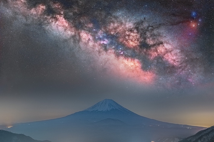 富士山とその上に広がる星空を映した夜景。
