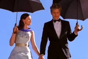 Rory and Logan in formal attire holding umbrellas.