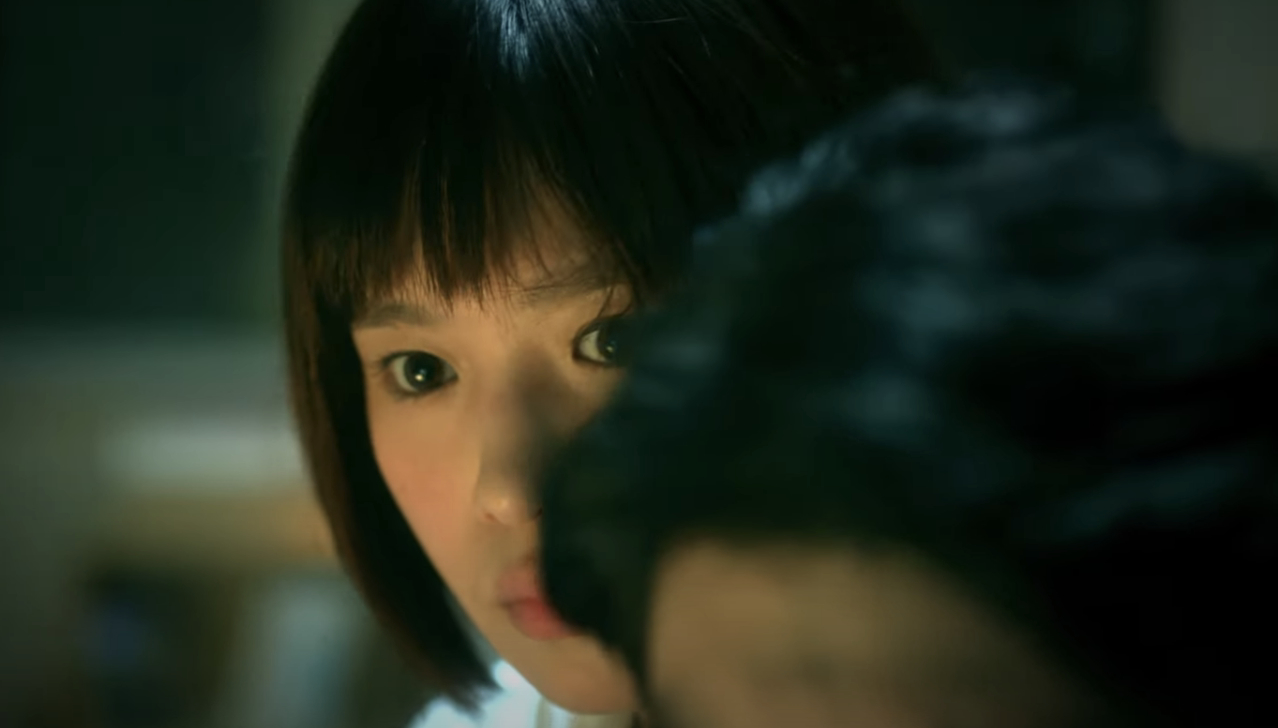 A frightened woman hides behind a man while they look at moniters