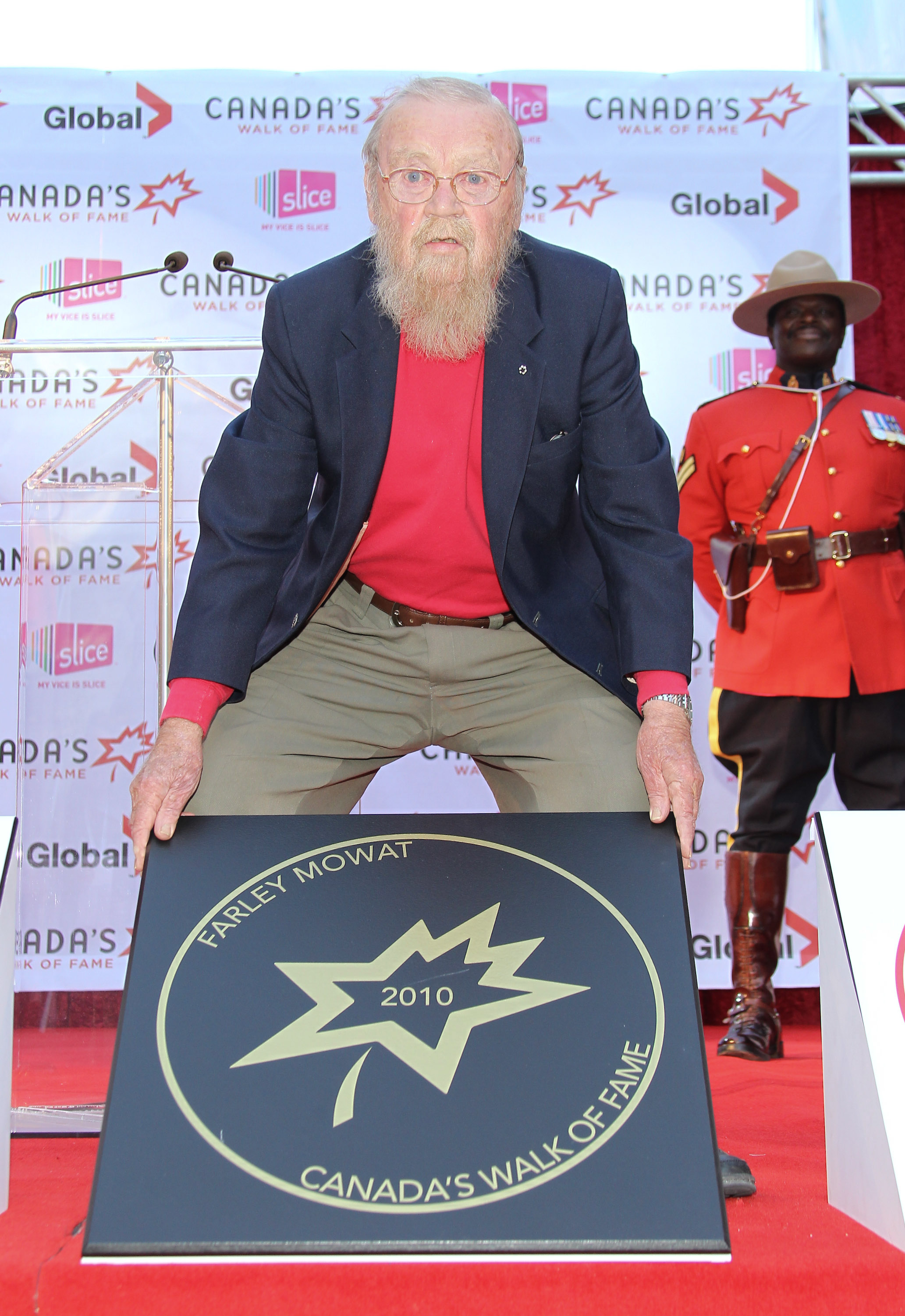 Farley Mowat holding his &quot;Canada's Walk of Fame 2010&quot; plaque, with a Royal Canadian Mounted Police officer in the background