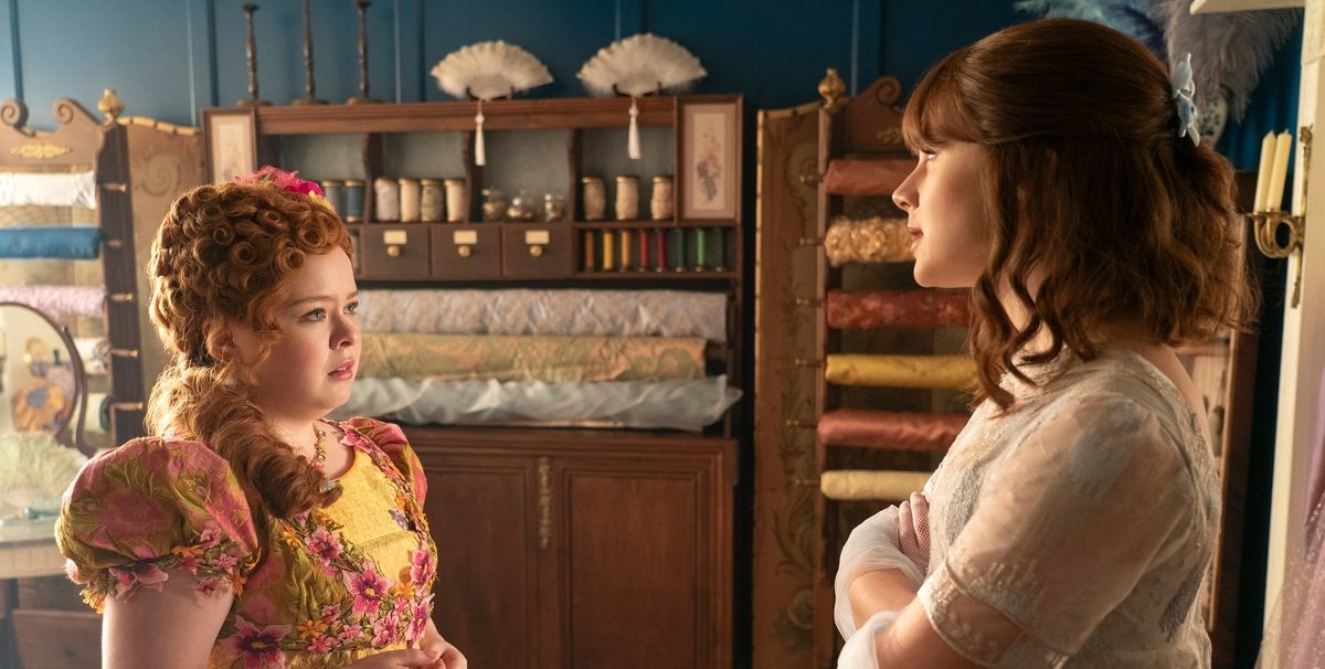 Nicola Coughlan, vestida de época, hablando con Claudia Jessie en una escena de la serie de televisión