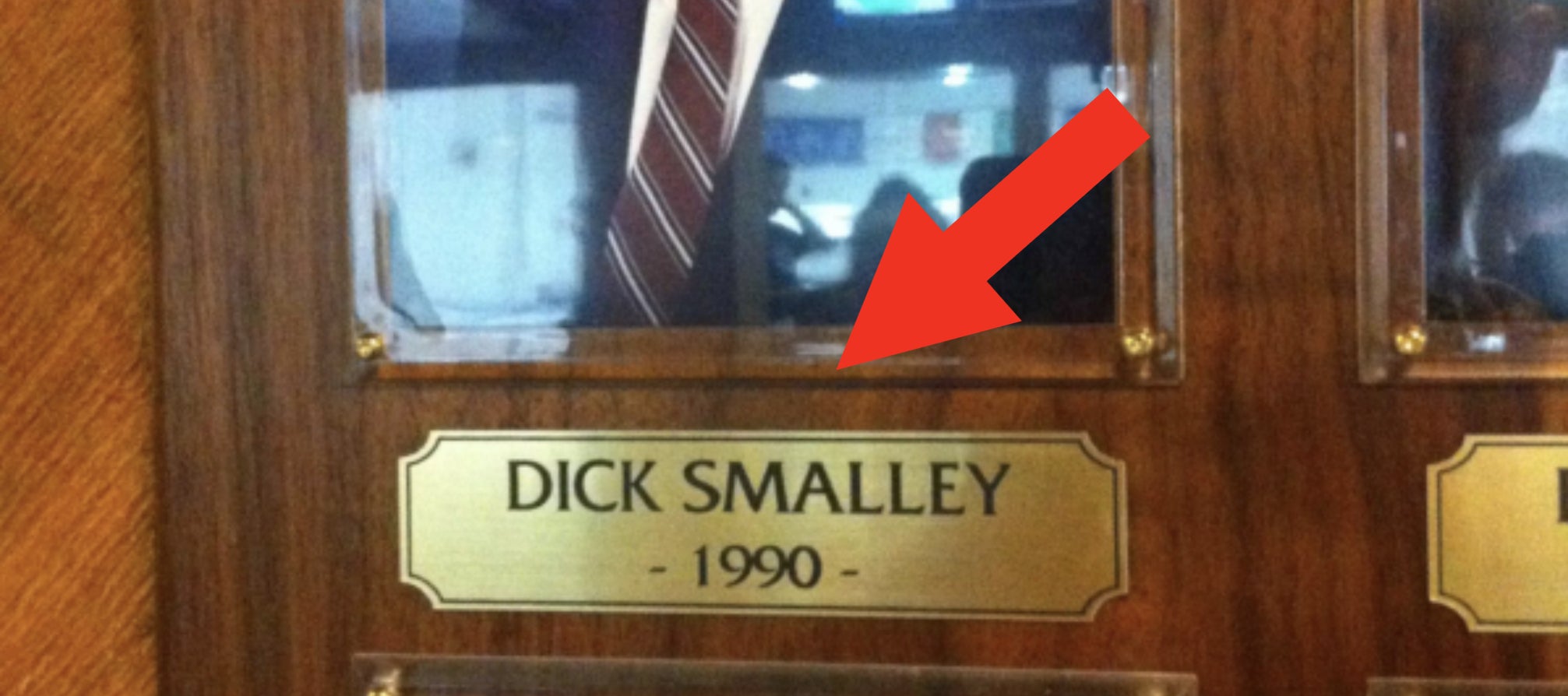 Framed portrait of Dick Smalley on a wood-paneled wall, displayed among other plaques