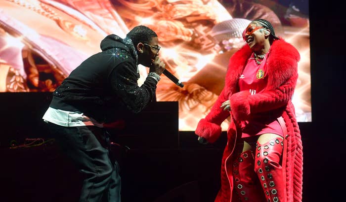 Two performers on stage, one in a red outfit with faux fur details, the other in black attire