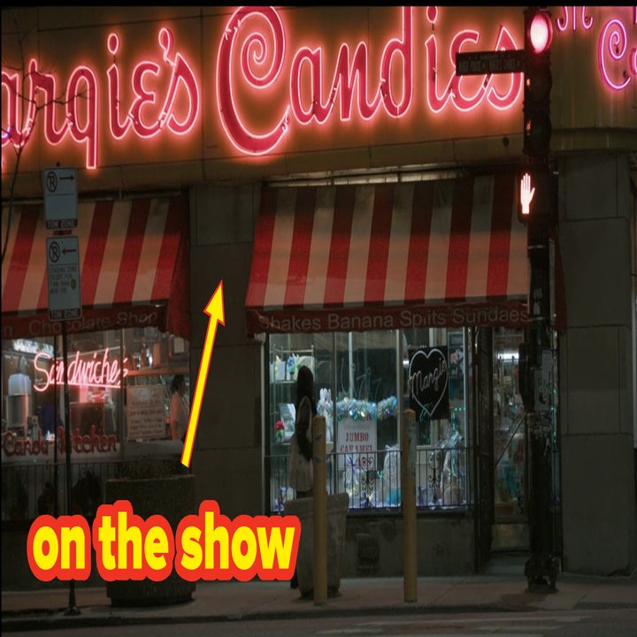 Exterior of Marguie's Candies shop at night with neon signs. A person stands outside, partially visible under the store's red and white striped awning