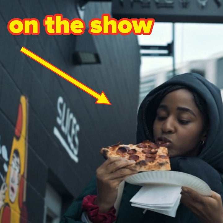 Sydney eating a slice of pizza on a street under an elevated subway train on The Bear
