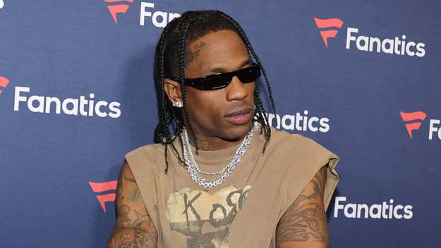 Travis Scott wears a sleeveless top and sunglasses on the red carpet at a Fanatics event