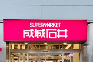 スーパーマーケットの入り口上に掲げられた「SUPERMARKET 成城石井」と書かれた看板。