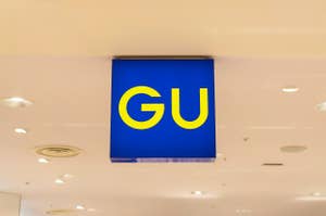 Sign with the letters "GU" hanging from a store ceiling, indicating a brand logo