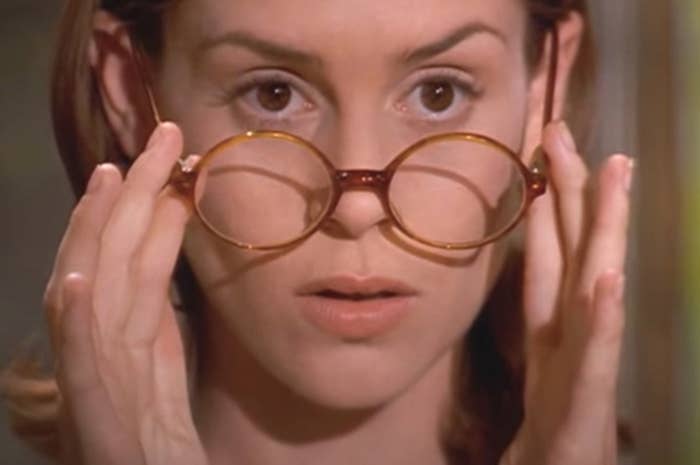 Woman holding glasses in front of her eyes, looking surprised