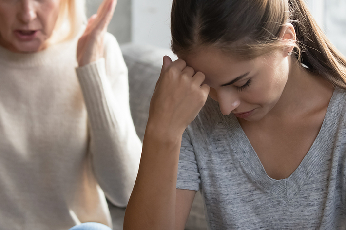 年配の女性と若い女性がソファに座り、年配の女性が手を挙げている様子を示す画像。