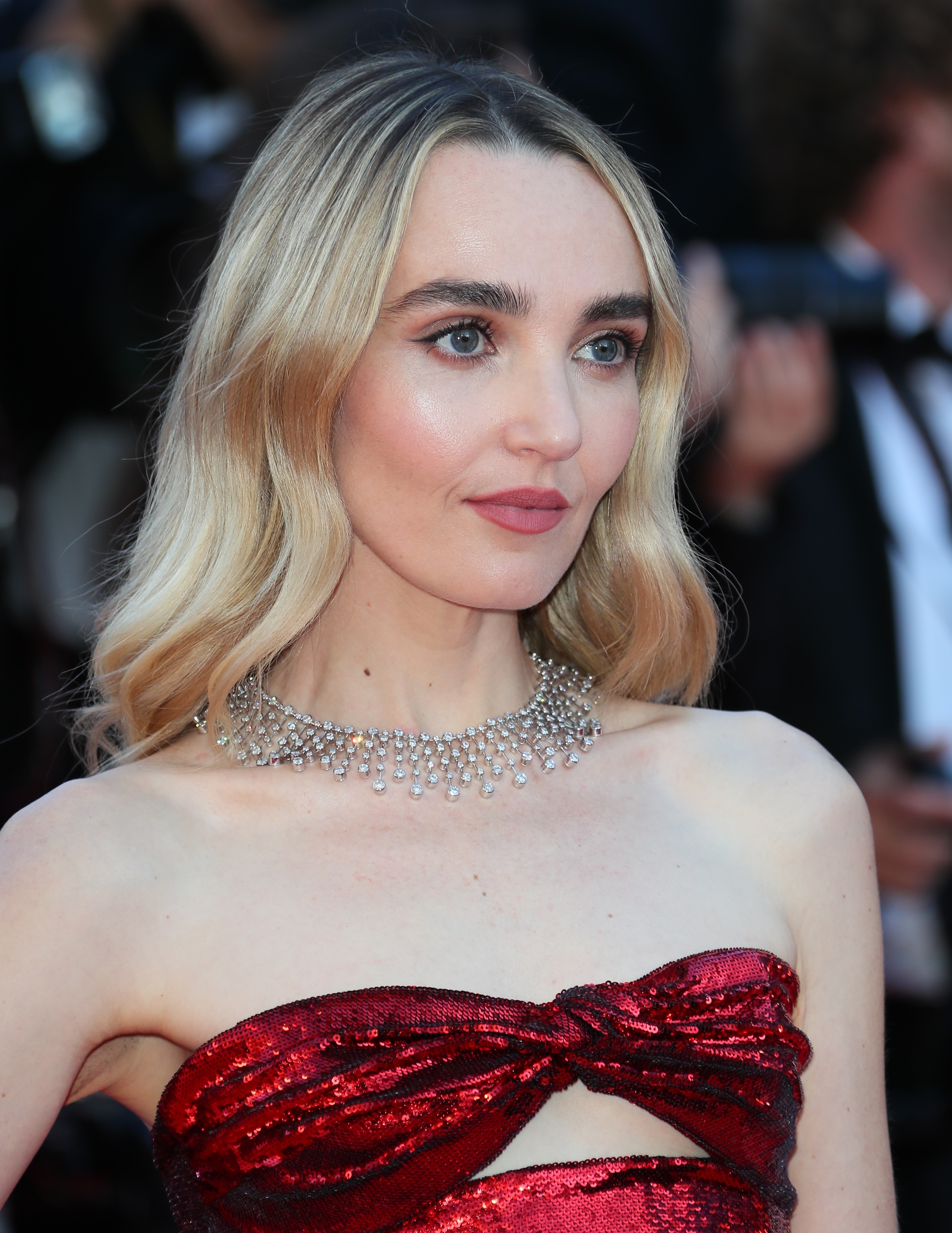 Chloe Fineman poses on the red carpet, wearing a strapless gown with a cut-out detail and a statement necklace