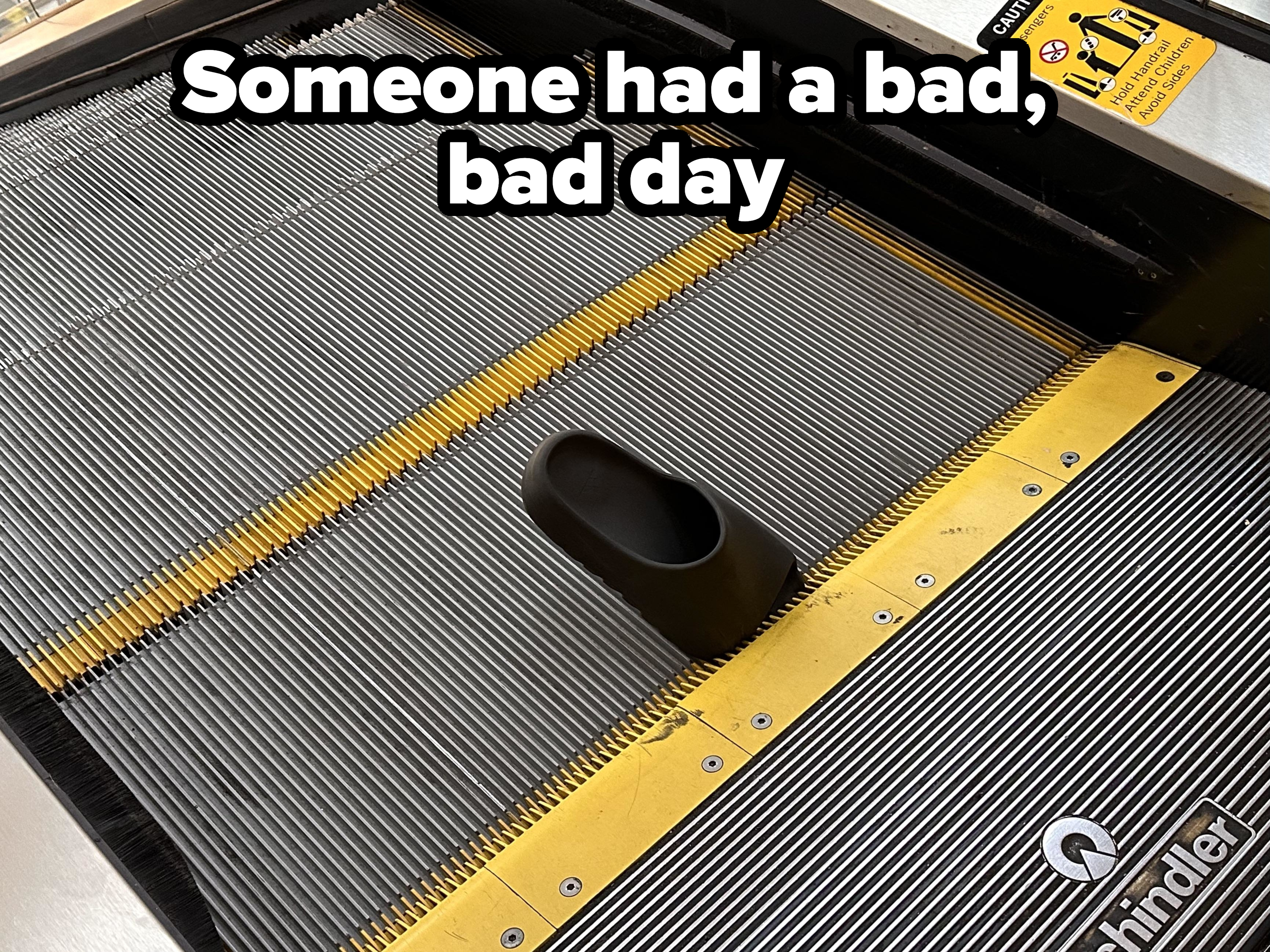 Close-up view of an escalator's step with a black comb plate and yellow safety markings at the edge