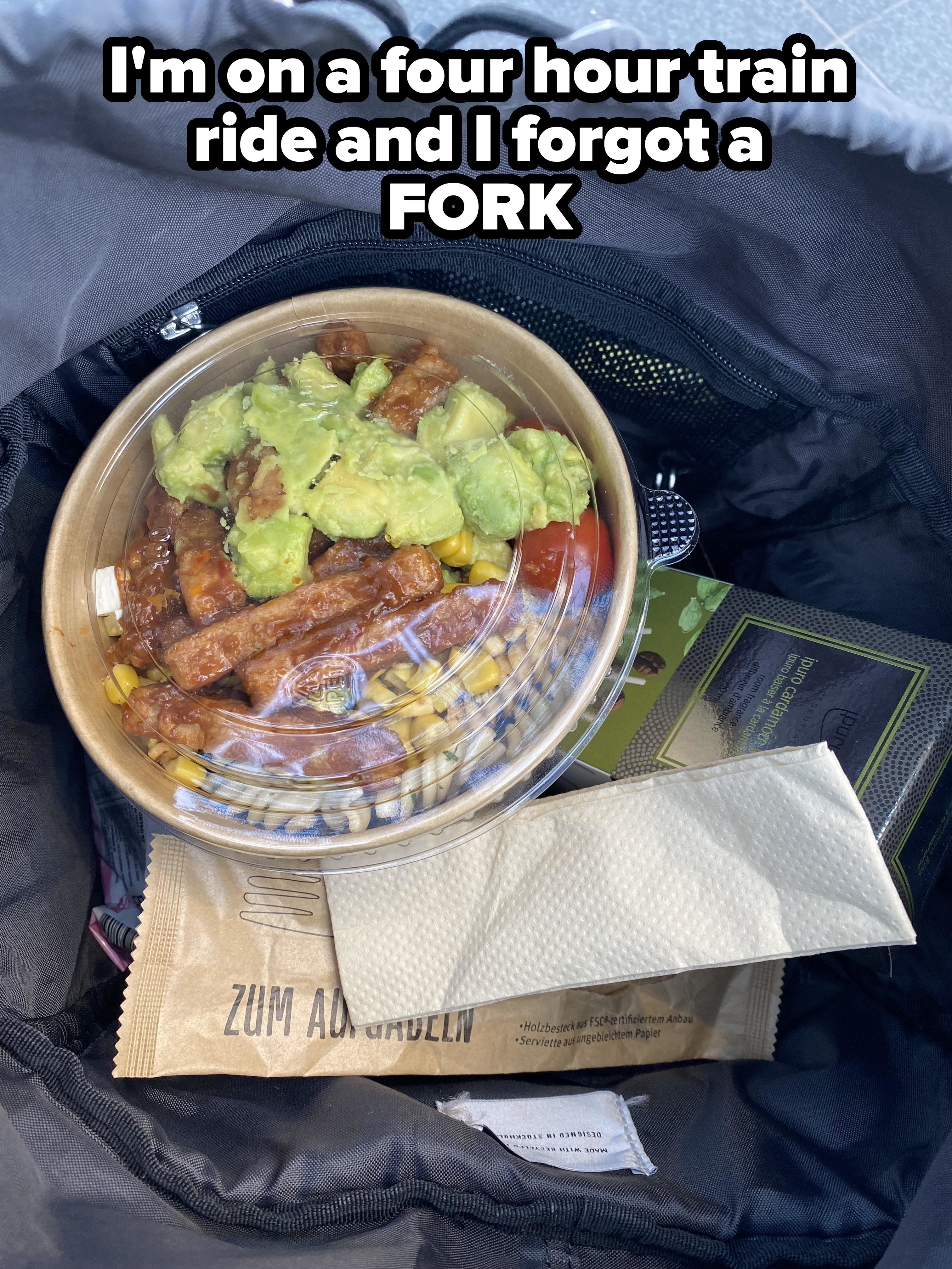A takeaway container with a bowl of food including avocado and meat inside a bag. Nearby are packaged food items and a brown napkin pack labeled "Zum Aufladen."