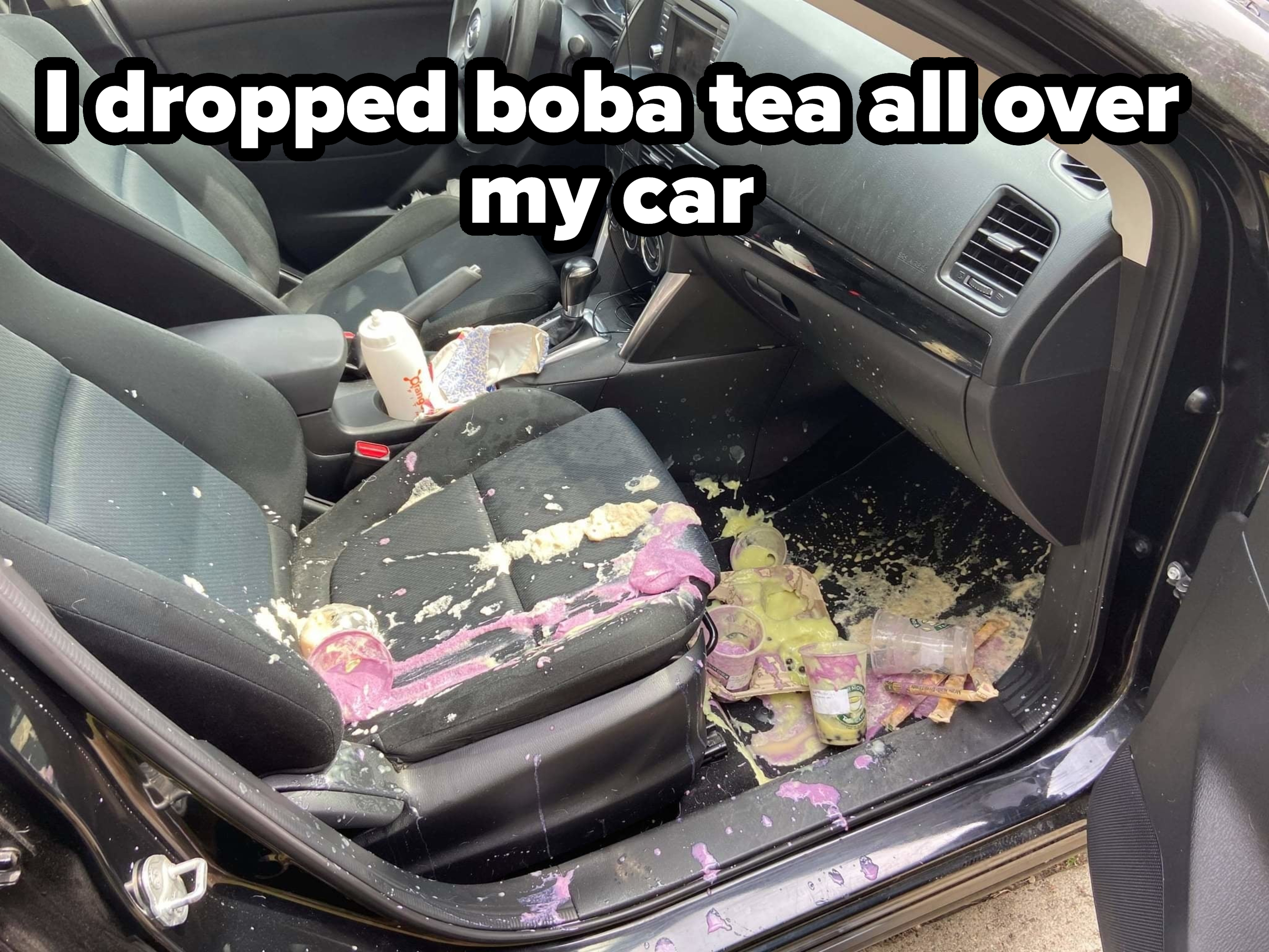 Car interior with yogurt and food spilled on seats and floor. Various containers and food items create a messy scene inside the vehicle