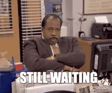 Stanley Hudson from The Office character sits at desk with arms crossed; “STILL WAITING” text is displayed