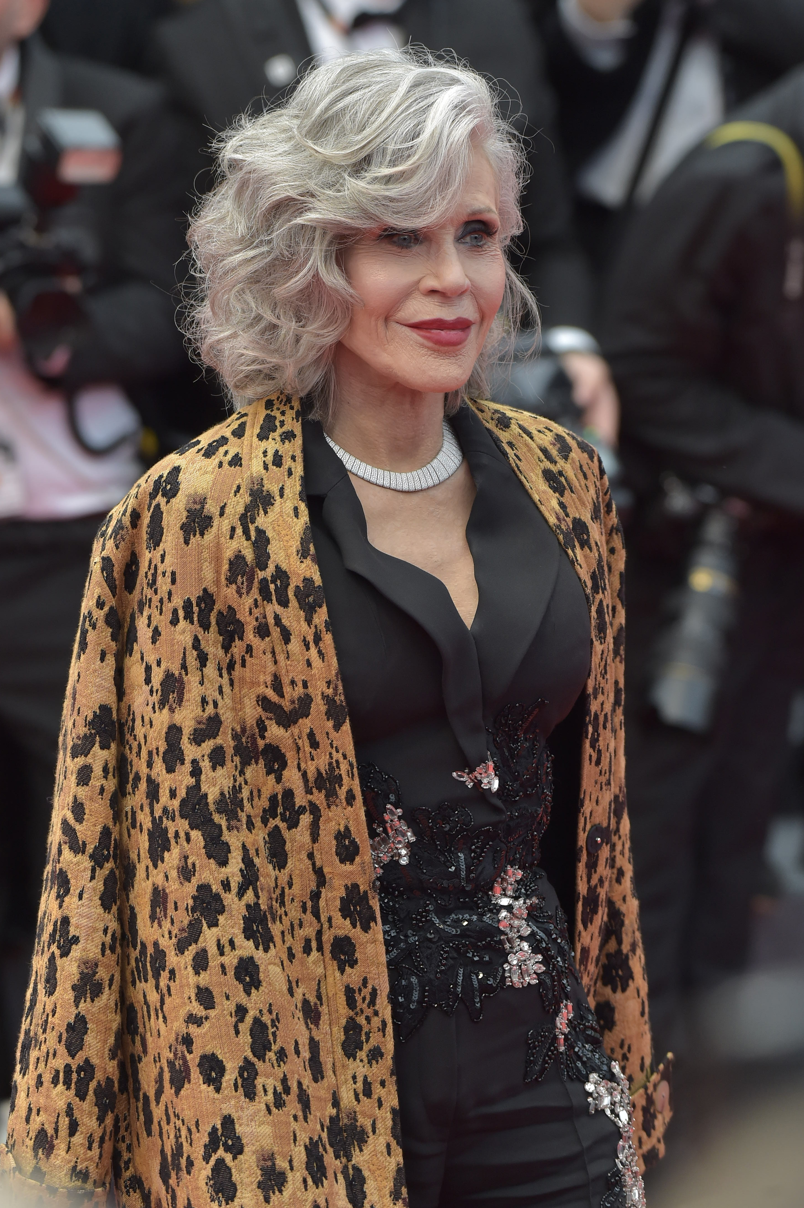 Jane Fonda wearing a black outfit adorned with floral embellishments and a leopard-print shawl at a public event