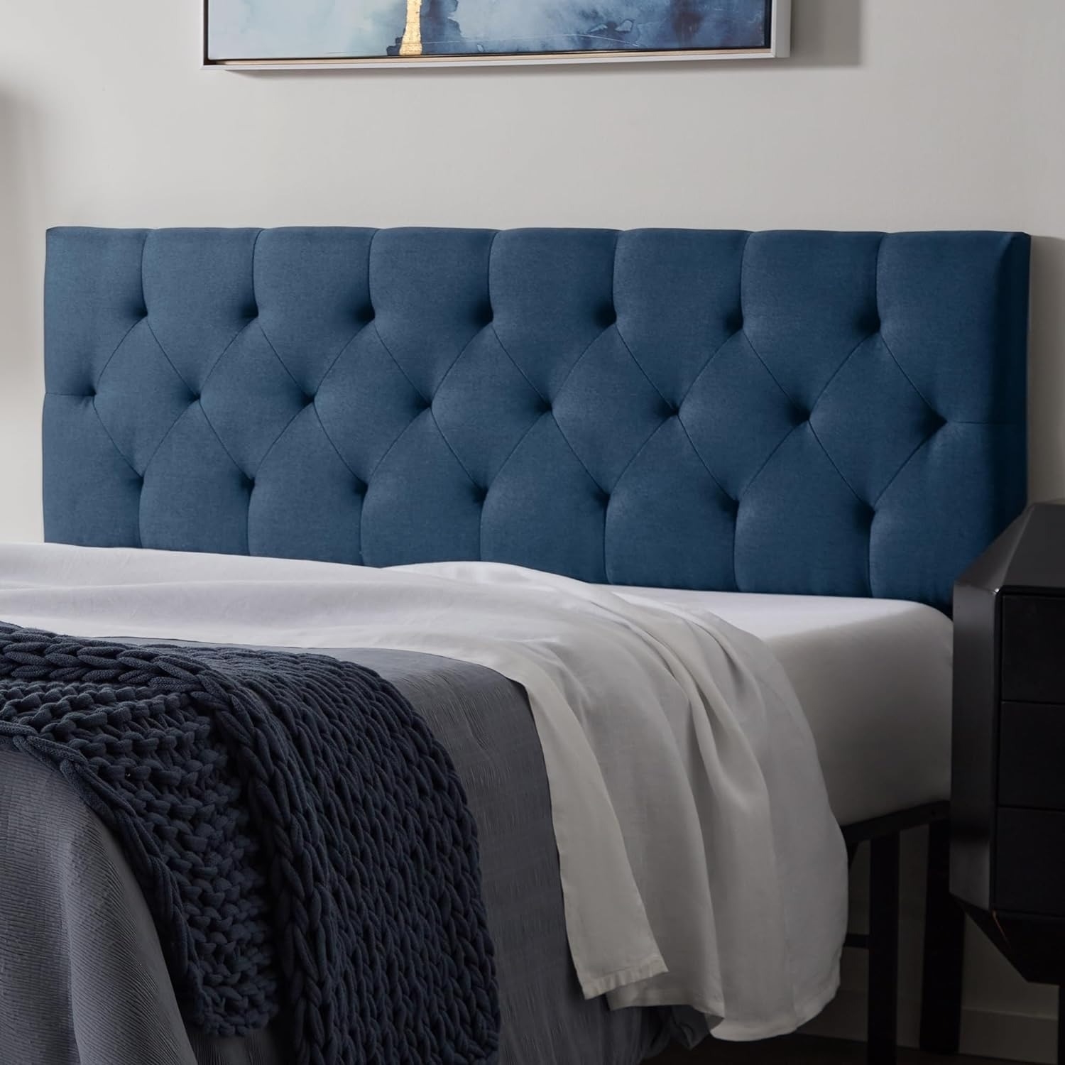 Tufted navy headboard with a diamond pattern in a bedroom setting