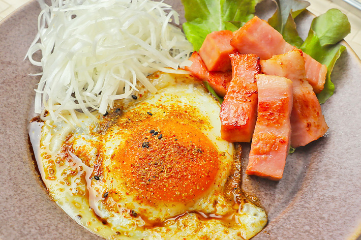 朝食の目玉焼き、ハム、サラダ、もやしを盛った皿。