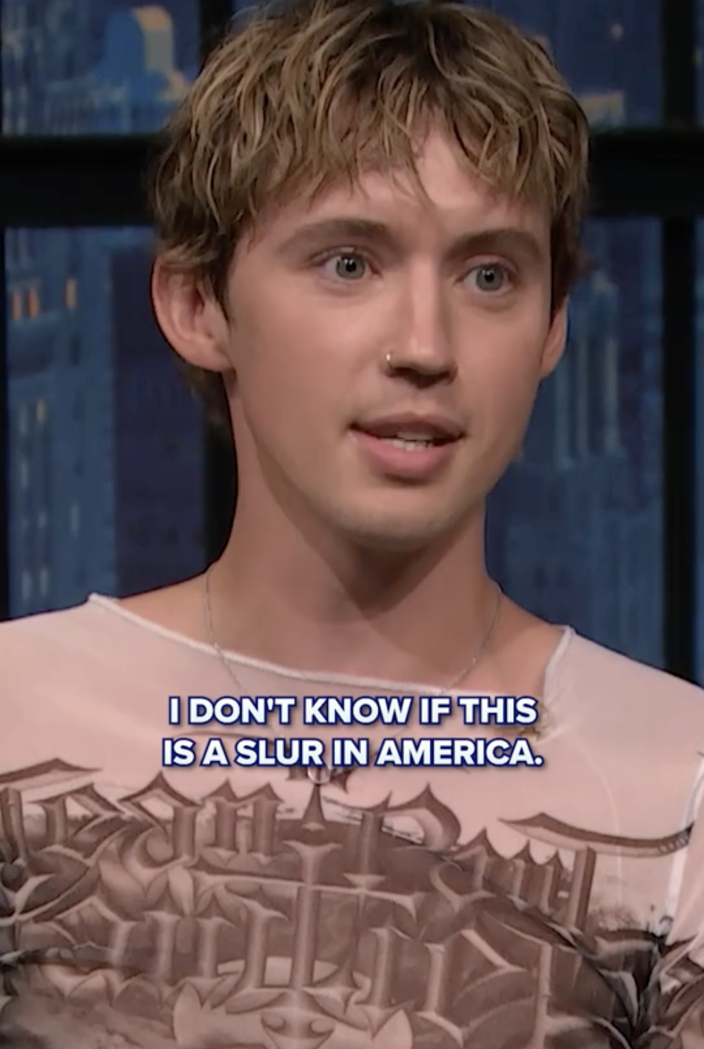 Person wearing graphic tee with text overlay from a TV show interview