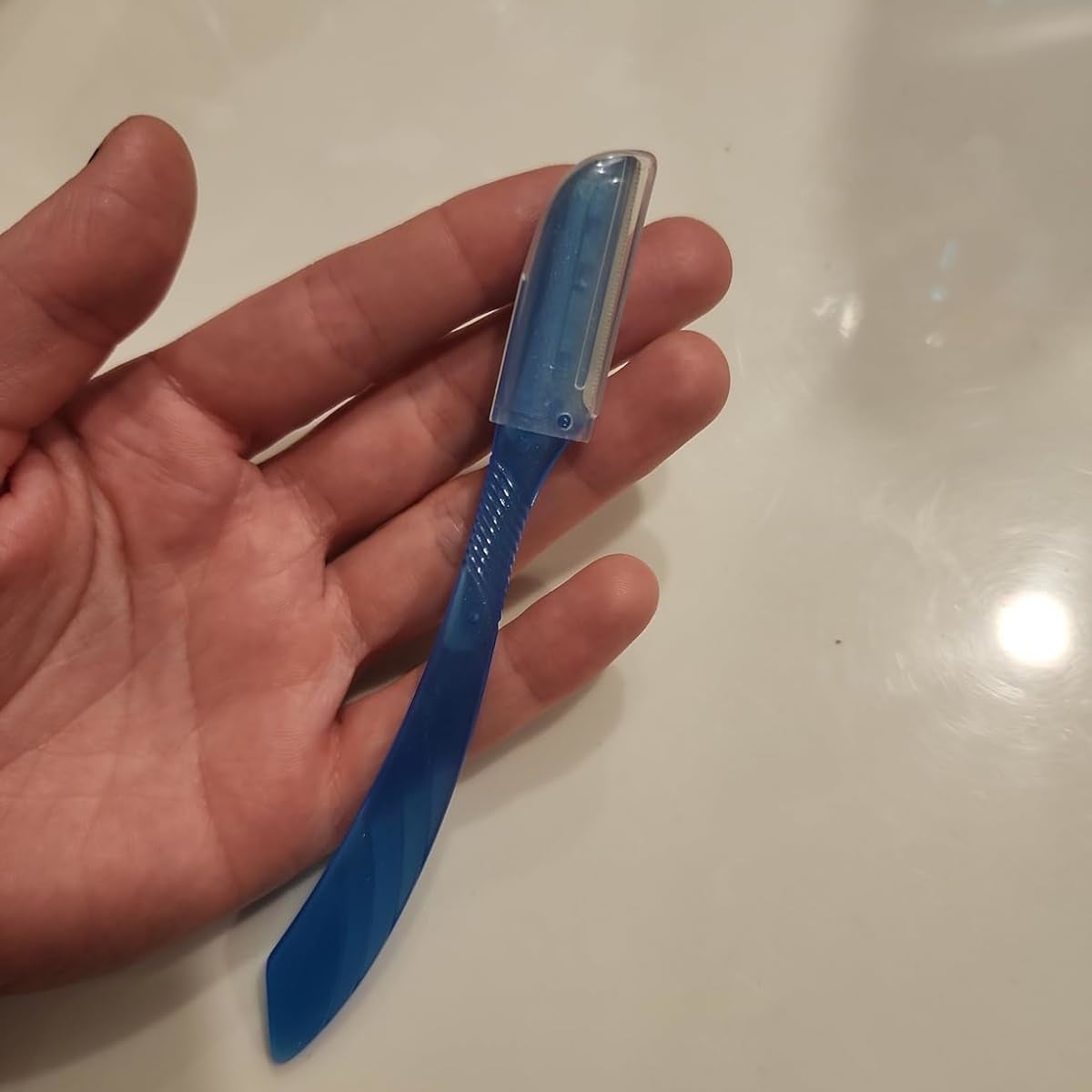 A hand holding a blue disposable plastic razor