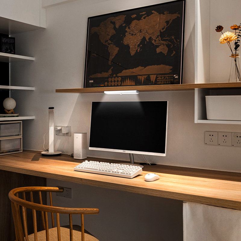 A tidy desk setup with a monitor, keyboard, mouse, and decorative items, with a world map artwork above