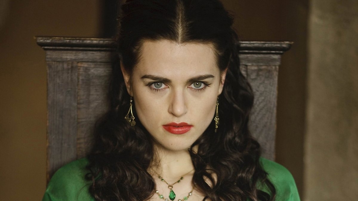 Close-up of Morgana from &quot;Merlin&quot; in green attire with a necklace and earrings