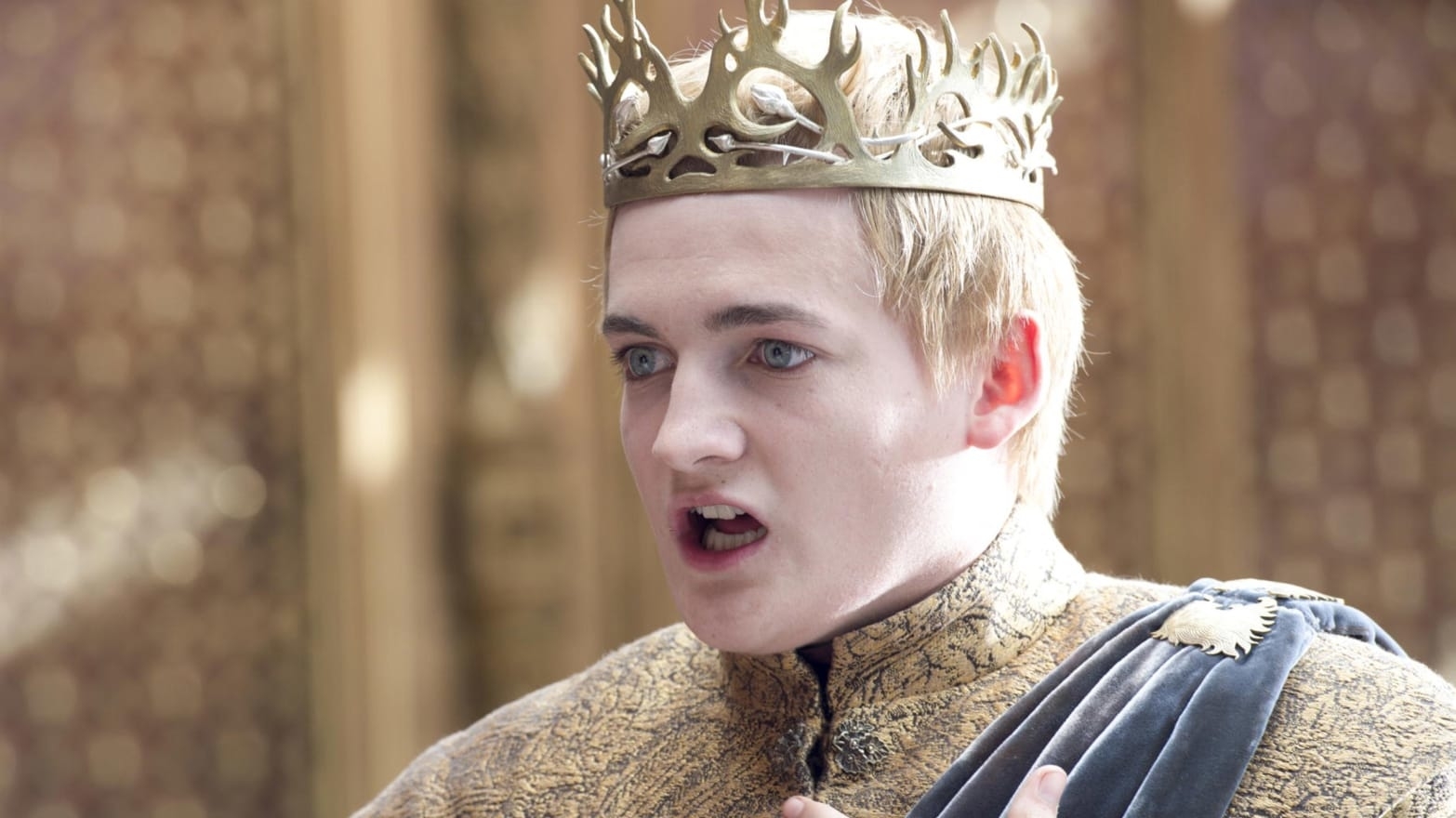 King Joffrey from Game of Thrones wearing a crown and royal attire, looking surprised