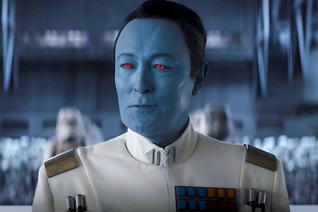 Grand Admiral Thrawn from Star Wars stands in a uniform, with red eyes and blue skin