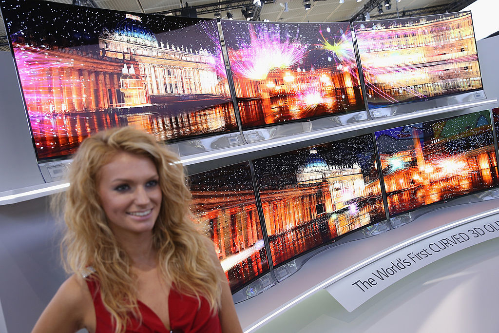 Woman standing beside the world&#x27;s first curved 3D TVs on display