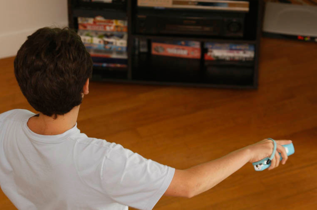 Person playing with a video game controller facing a TV stand with games