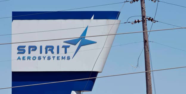 Spirit AeroSystems sign on a building exterior, partially obscured by power lines against a clear sky