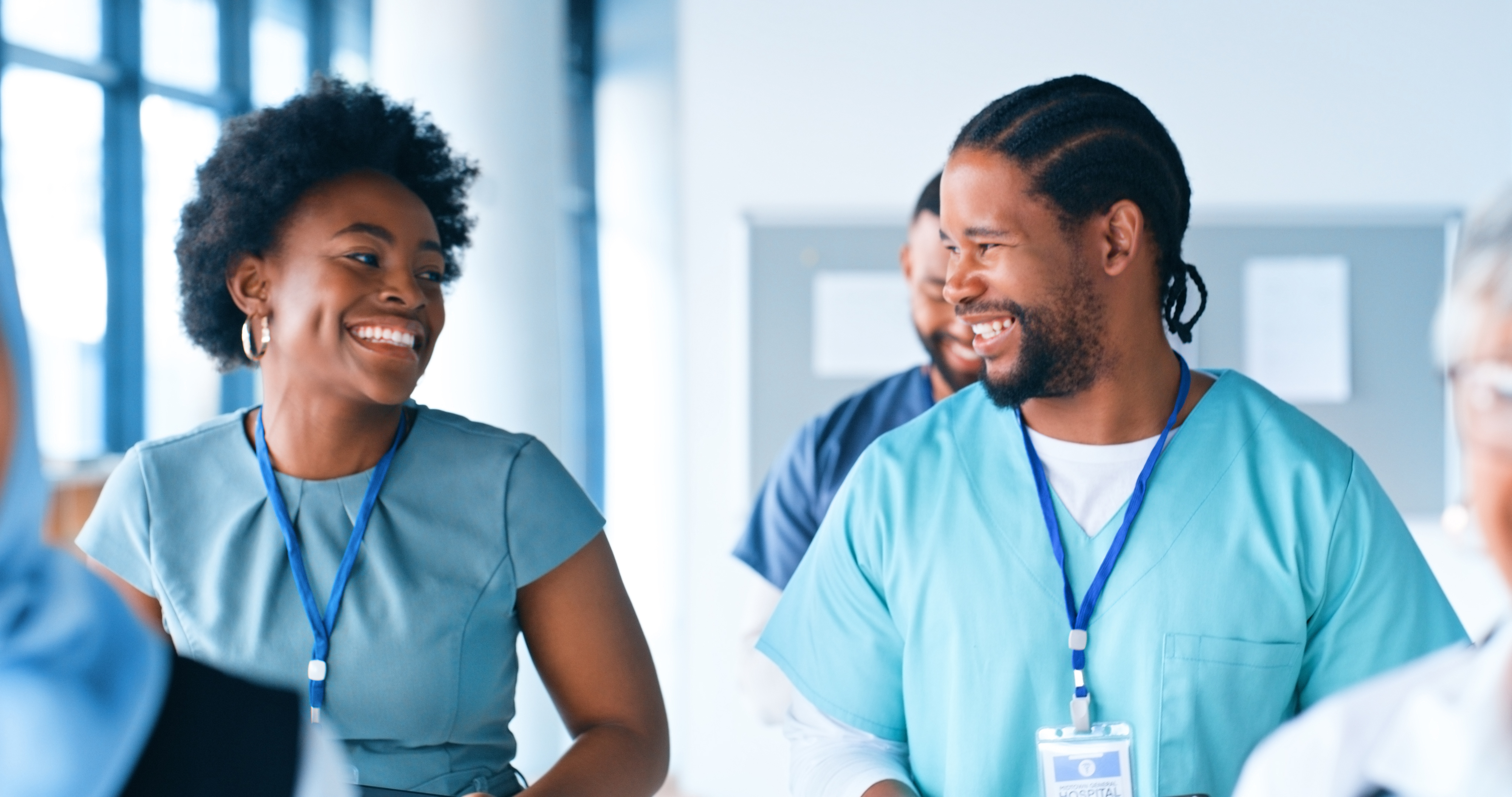 Two healthcare professionals in scrubs engaging in a cheerful conversation at the workplace