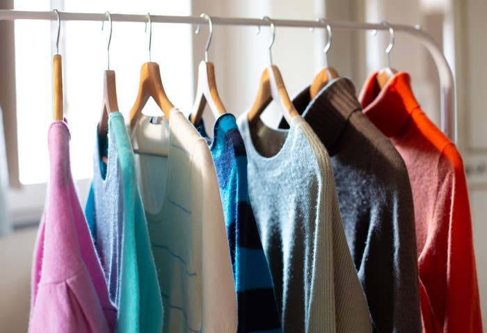 Assorted sweaters on hangers in a bright room, trendy and cozy fashion choices