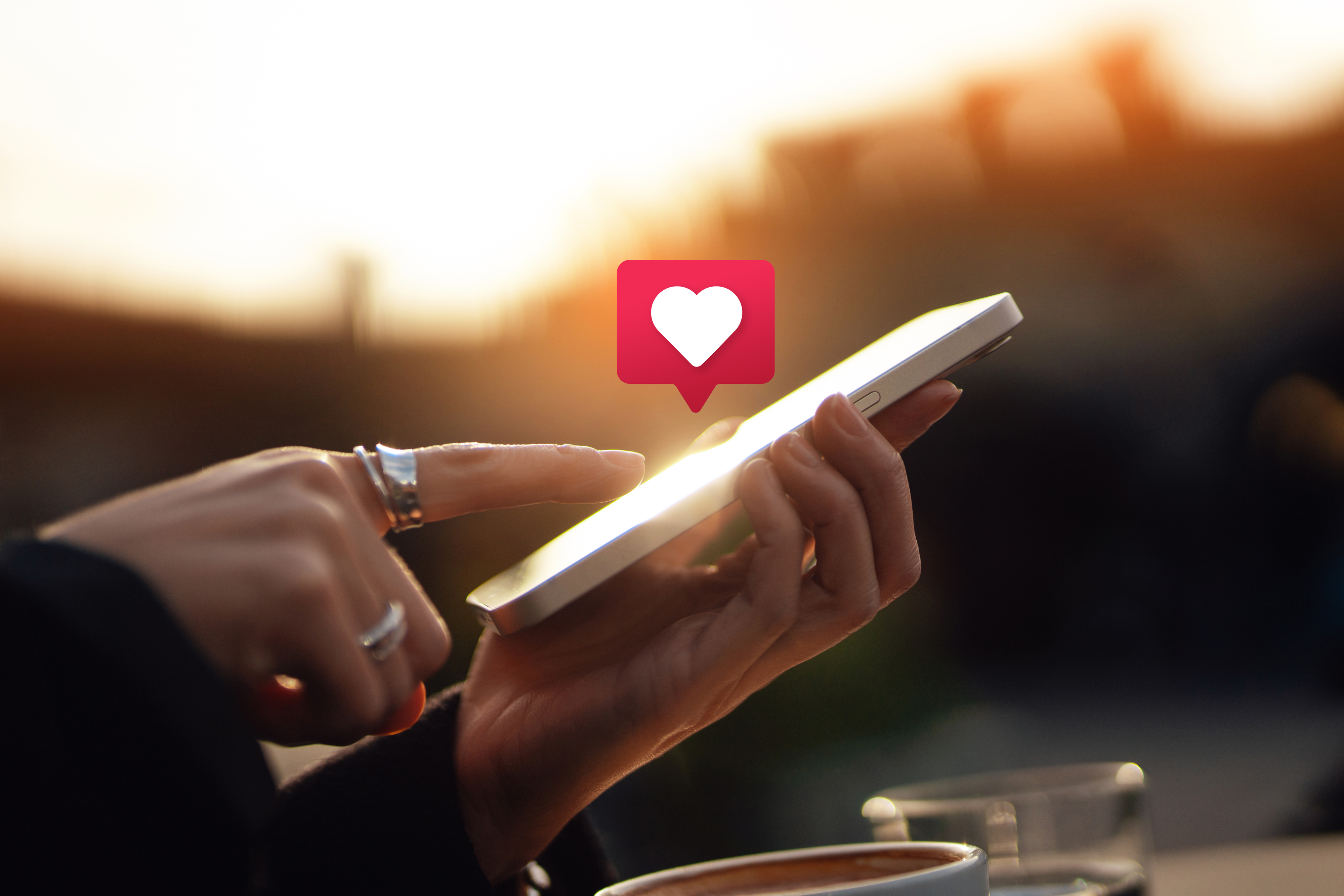 Person using a smartphone with a notification pop-up of a heart symbol, indicating a like or love reaction