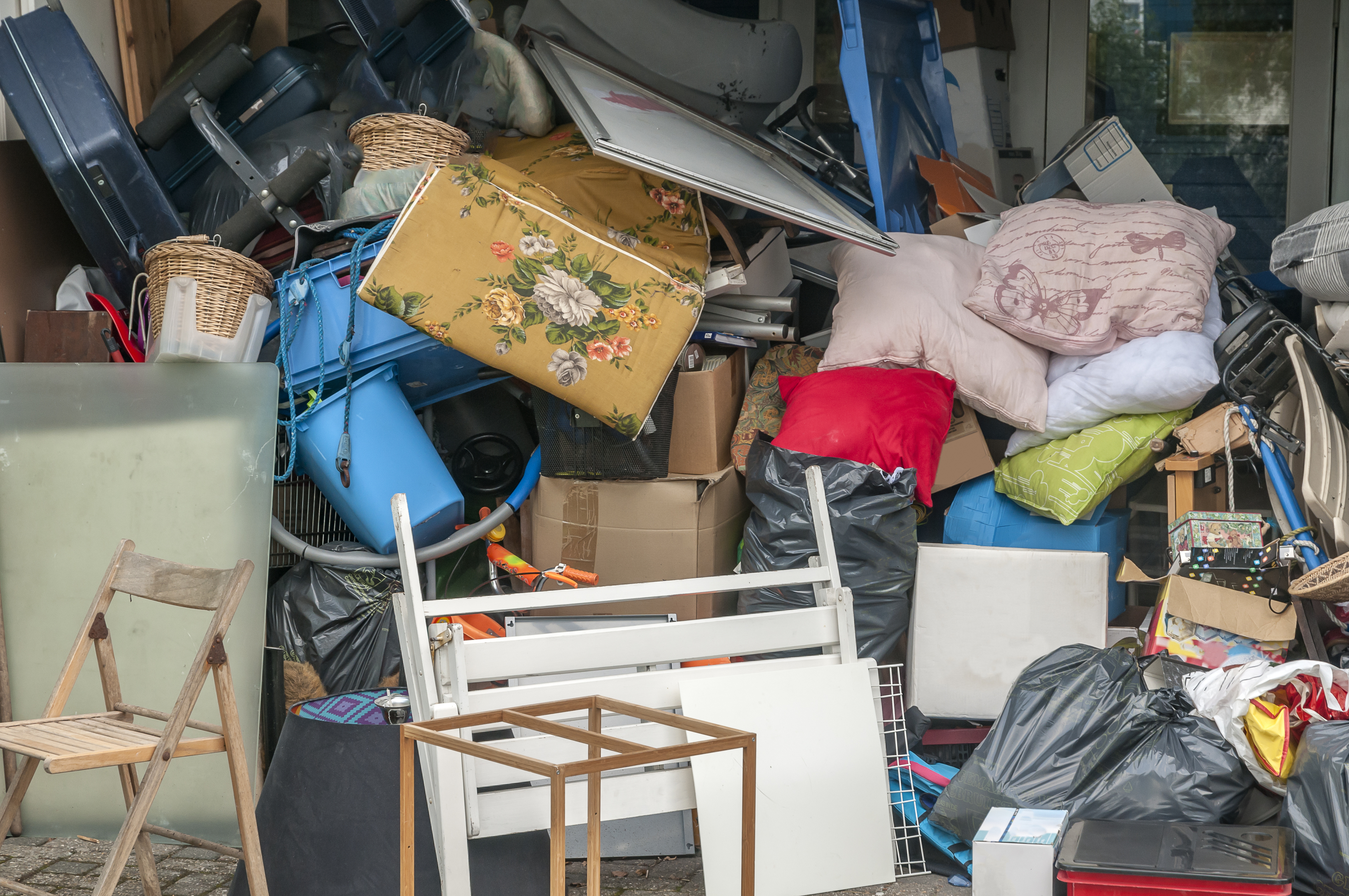 A cluttered space filled with assorted discarded items such as furniture and household goods, overflowing from a room
