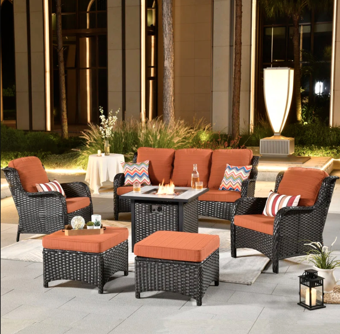 Patio seating arrangement with sofa, chairs, and a fire table centerpiece at night