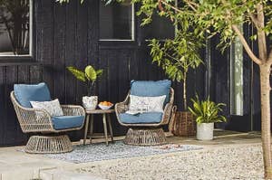 Two wicker chairs with cushions and a small table set on a patio for outdoor relaxation