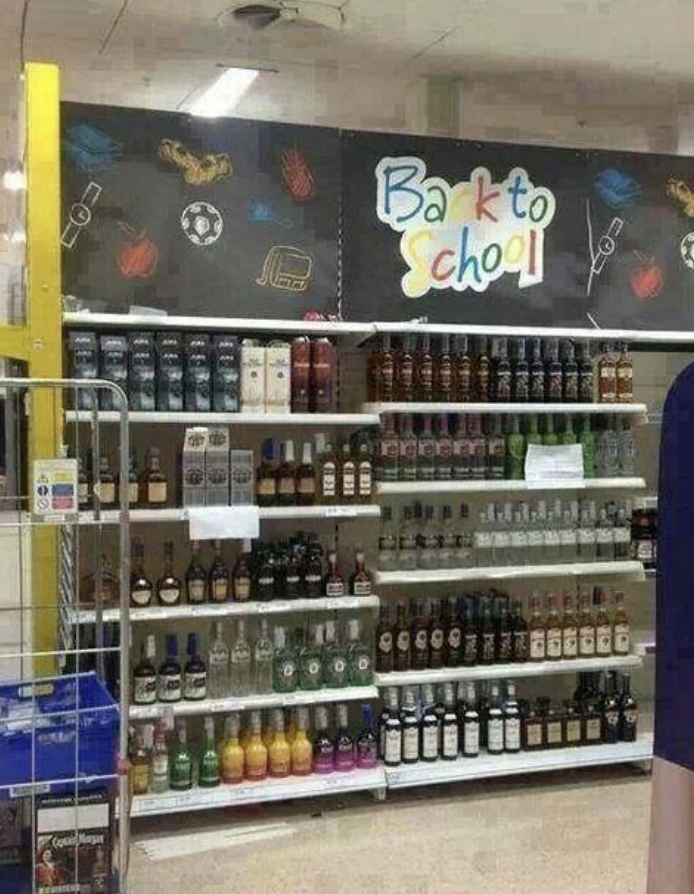 Sign reads &#x27;Back to School&#x27; above a liquor shelf in a store, implying humor in the context