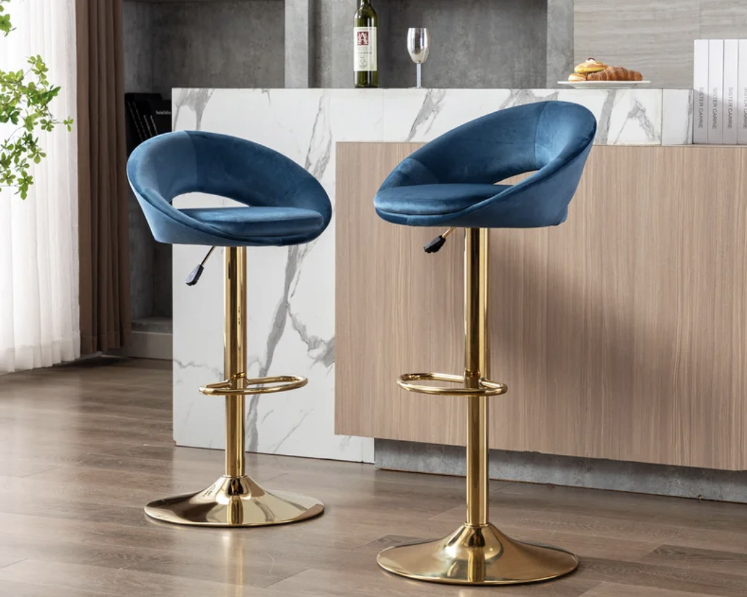 Two contemporary blue velvet bar stools with gold-tone bases in a modern kitchen setting