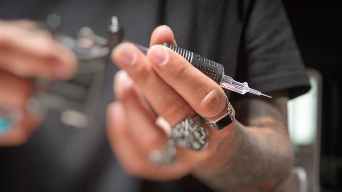 Close-up of a tattoo artist&#x27;s hands preparing a tattoo machine and needle